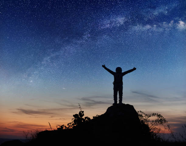 istock Astronaut standing on top of mountain under night sky. 1210750196