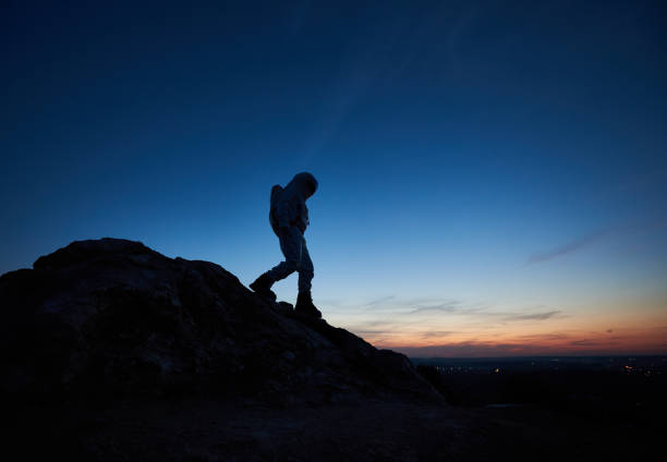 istock Astronaut walking down the rocky hill under blue sky. 1210750197