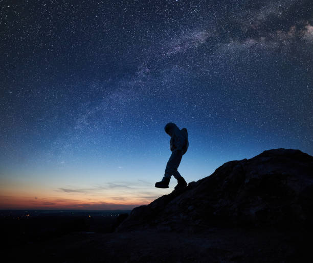 istock Space traveler walking down the rocky hill under starry sky. 1210750202