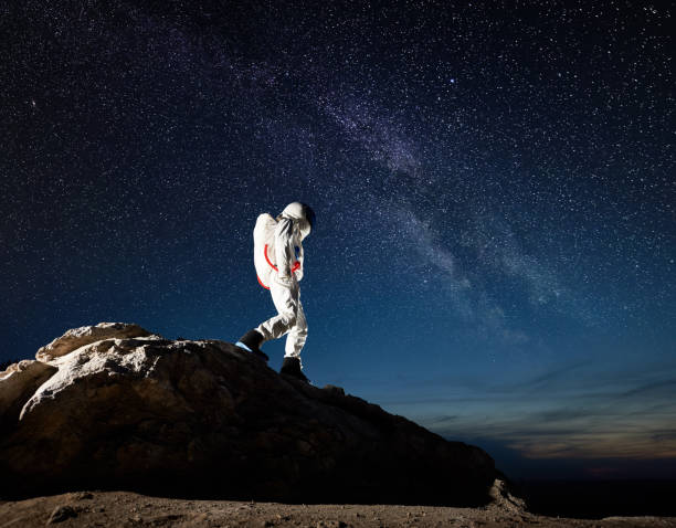istock Space traveler walking down the mountain under starry sky. 1210750214