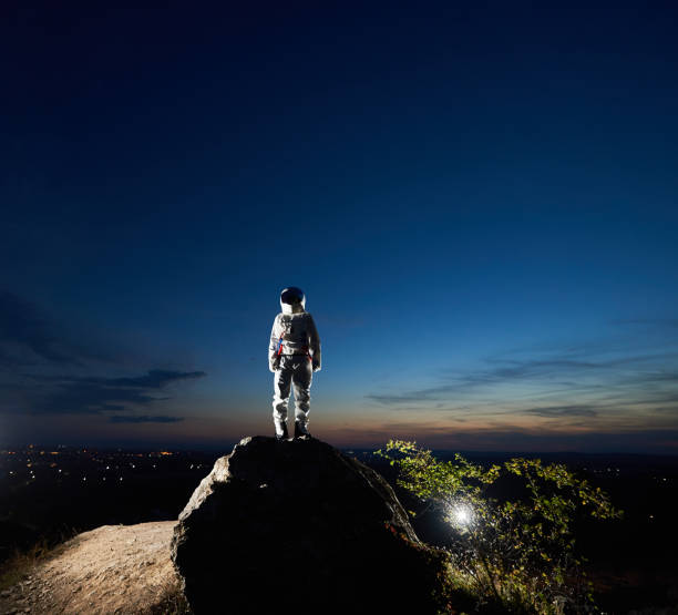 istock Astronaut standing on top of mountain under night sky. 1210750223