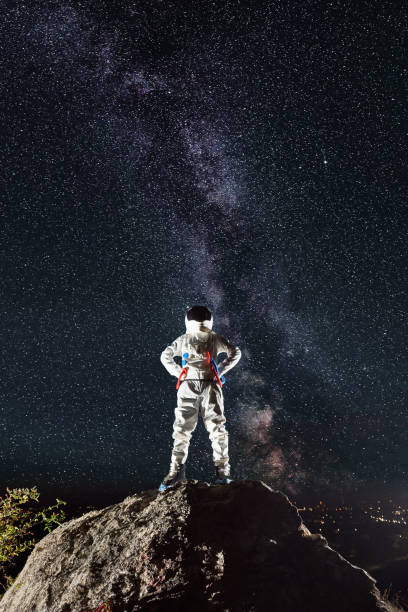istock Spaceman standing on rocky mountain under starry sky. 1210750264