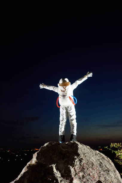 istock Spaceman standing on rocky hill under beautiful night sky. 1210750271