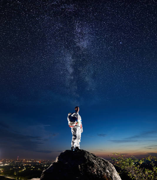 istock Astronaut standing on rocky mountain under night starry sky. 1210750315