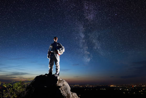 istock Astronaut standing on rocky mountain under night starry sky. 1210750328