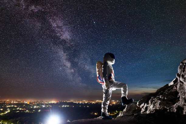 istock Spaceman standing on rocky mountain under starry sky. 1210750348