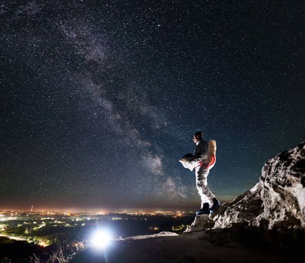 istock Astronaut standing on rocky mountain under fantastic starry sky. 1210750356