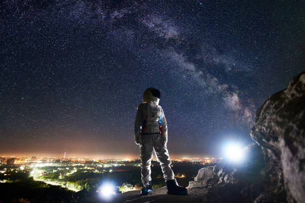 istock Spaceman standing on rocky mountain under night sky with stars. 1210750373