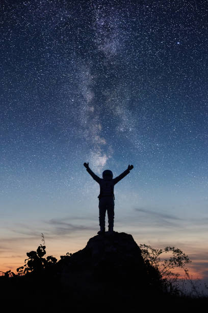 istock Astronaut standing on top of mountain under night sky. 1210750484