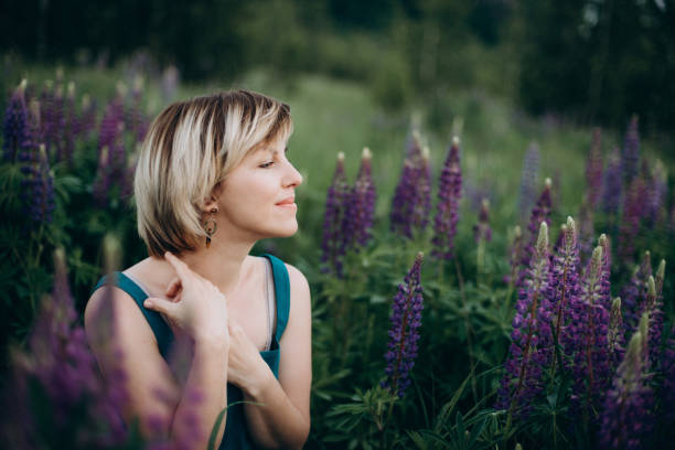 schöne romantische mädchen in einem blauen kleid in einem feld von lupinen blumen. weicher selektiver fokus. - lupine single flower flower blue stock-fotos und bilder