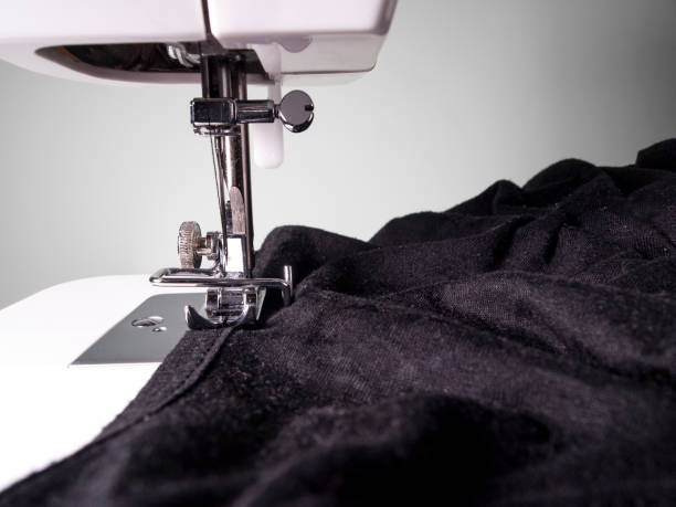 istock Sewing machine detail with a black fabric on a white wall background 1210753573
