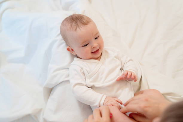 istock baby in white clothes lying on his back on bed 1210755003