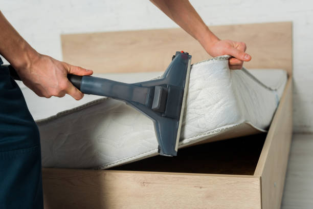 cropped view of man removing dust on mattress with vacuum cleaner stock photo