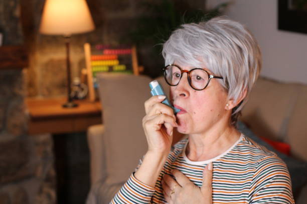 istock Senior woman using asthma inhaler at home 1210757798