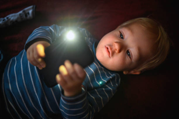 istock Cute boy holding mobile phone and lying on back on the floor 1210759459