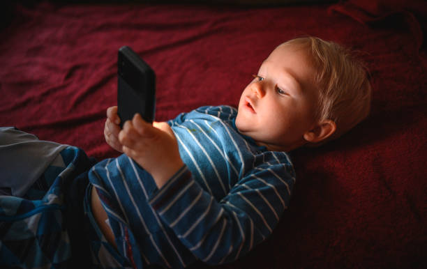 istock Cute boy holding mobile phone and lying on back on the floor 1210759466