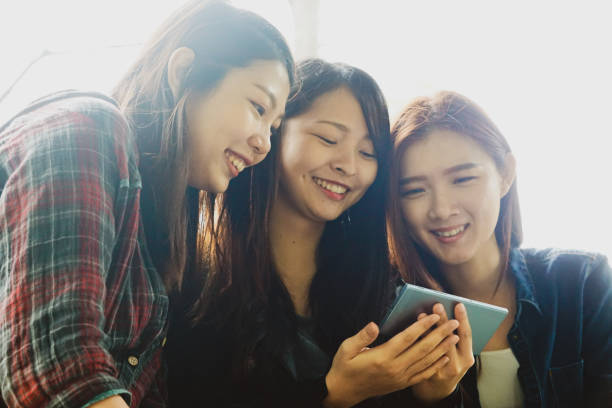 istock Three beautiful girls looking on the phone with smiling face 1210759805