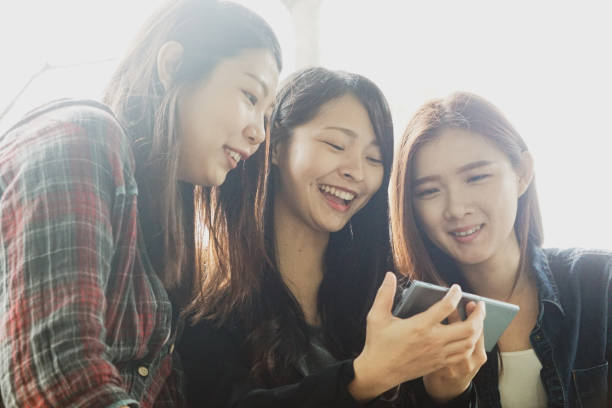 istock Three beautiful girls looking on the phone with smiling face 1210759816
