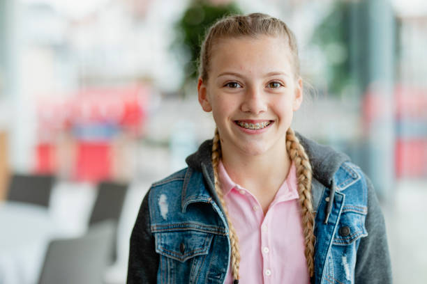 Confident teenage girl with braces, smiling at camera Adolescent blond girl with plaits smiling confidently, youth, aspiration, growing up 15 year old blonde girl stock pictures, royalty-free photos & images