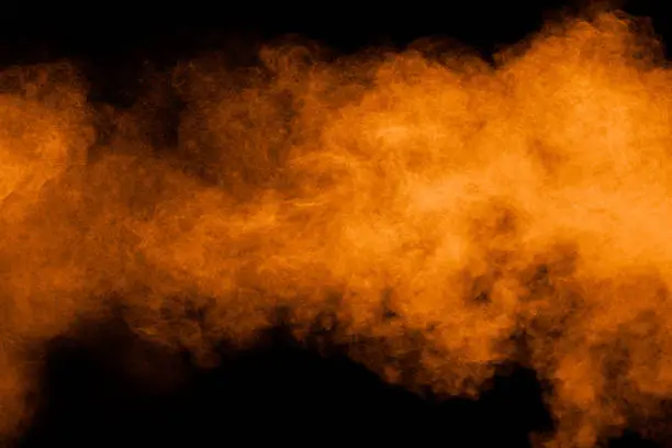 Photo of Orange powder explosion on black background. Orange color dust splash.