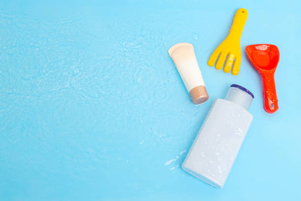 日焼け止めクリームspfローションは、プールの青い水面にカラフルな水のおもちゃで太陽から子供の肌を改善するために、トップビュー。コンセプト紫外線保護製品、夏の子供用化粧品。