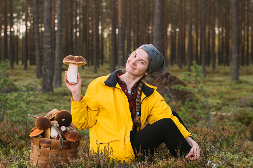 Girl with pleasure of size of porcini mushroom in the forest