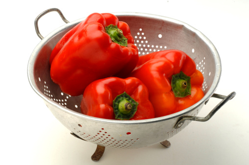 red peppers in a colander on a white background