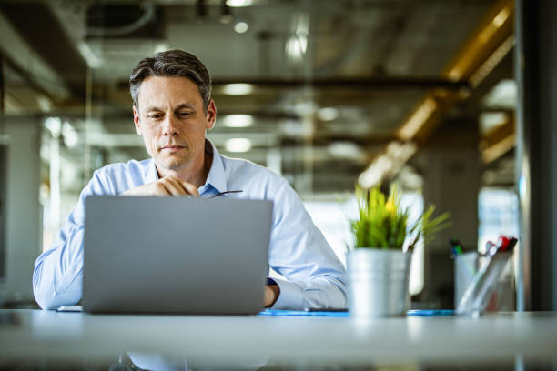 istock Male entrepreneur reading an e-mail on laptop in the office. 1210771196