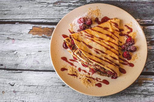 Top view of pancake with raspberries isolated on wooden background