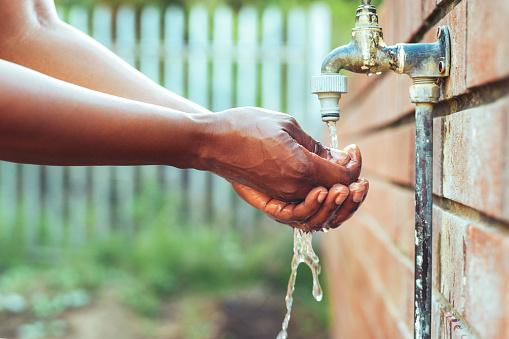 Cropped shot of an unrecognizable woman washing her hands outdoors