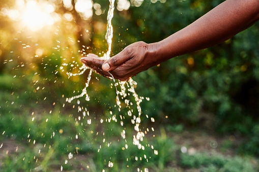 Cropped shot of an unrecognizable woman’s hands under a stream of running water outdoors