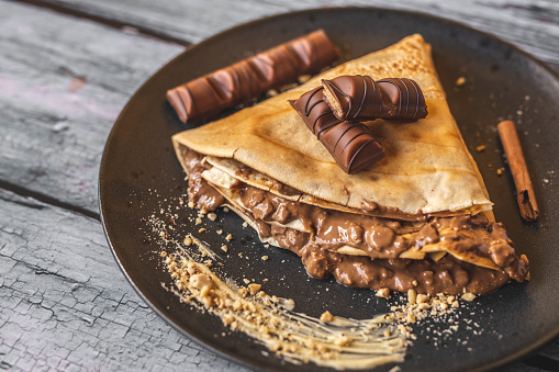 Pancake with chocolate on wooden background