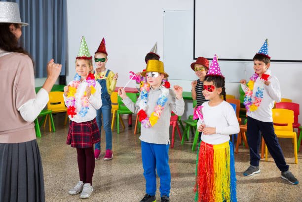 istock Kids and teacher in funny hats dancing 1210775686