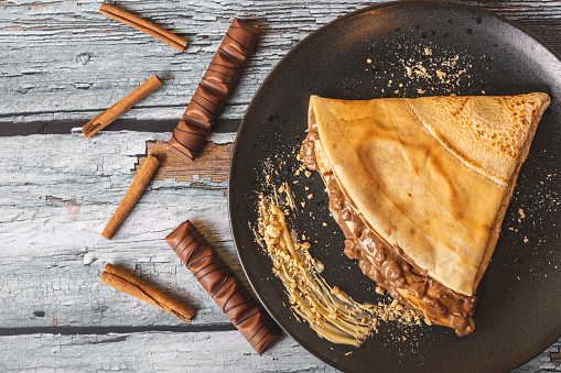 Top view of pancake, chocolate and cinnamon isolated on wooden background