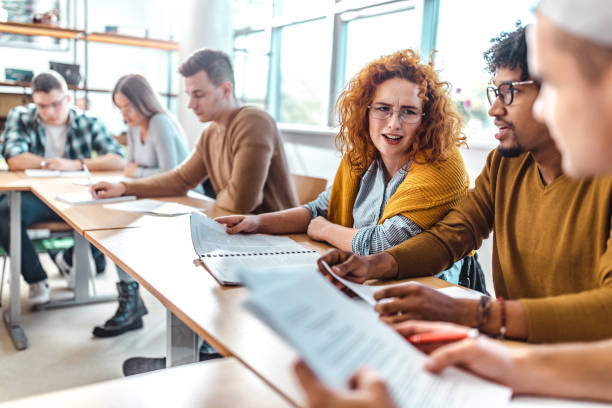 istock Happy college students talking while studying in the classroom. 1210777641