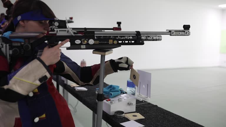 Teenage girl practicing air rifle shooting at shooting range