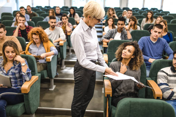 istock Female college student talking to senior professor on a class at lecture hall. 1210777982