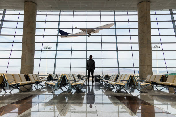 hombre de negocios con equipaje esperando en el aeropuerto - airplane passenger indoors inside of fotografías e imágenes de stock