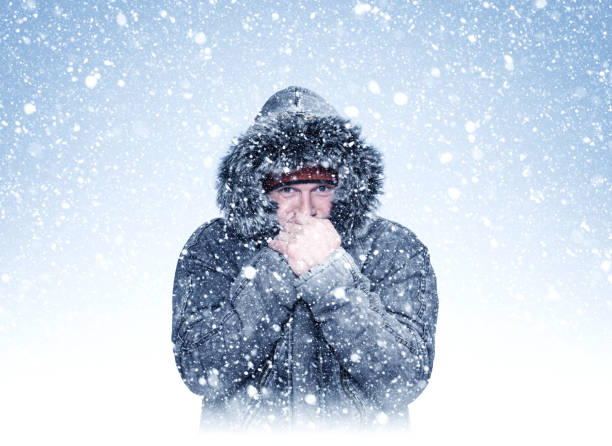 Frozen man in winter clothes warms his hands, cold, snow, frost, blizzard
