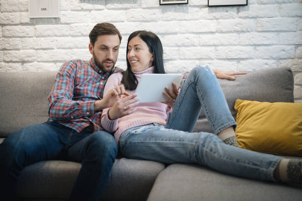 istock Smiling young couple using digital tablet at home 1210788414