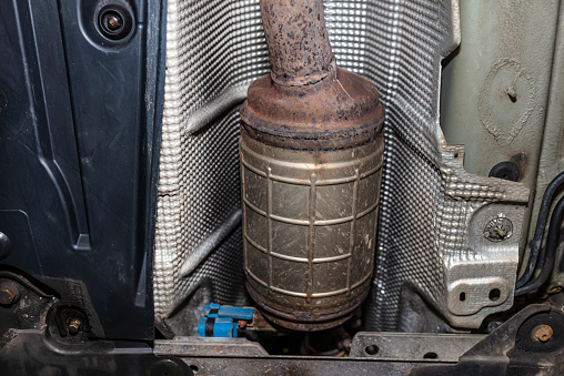 Un filtro de partículas diésel en el sistema de escape en un coche en un ascensor en un taller de coches, visto desde abajo. photo