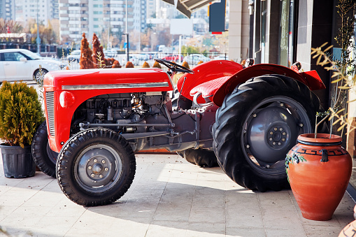 Decorative red tractor parked in front of a shop in the city