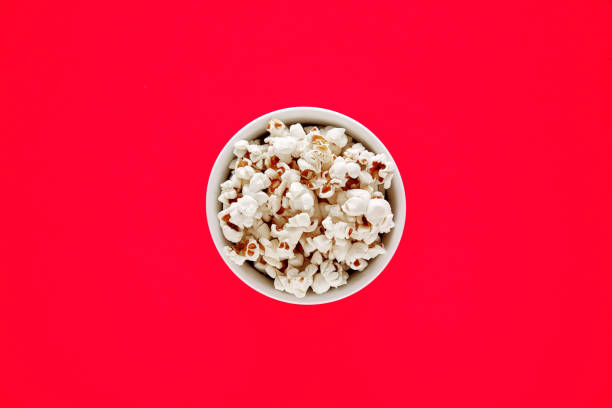 istock Popcorn in a white bowl on red background 1210790581