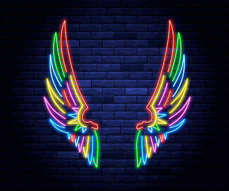 Colorful illuminated neon angel wings. Light electric banner glowing on background of bricks wall.