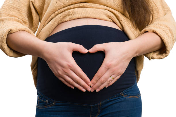 istock Close-up of future mom making heart shape on her tummy 1210791180