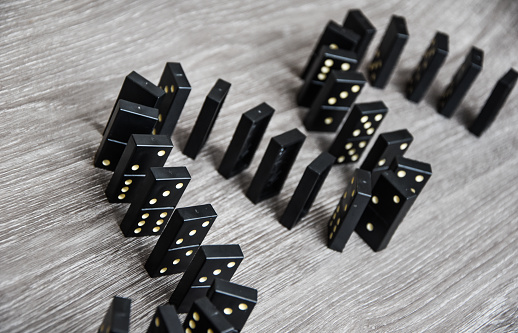 black dominoes on a light wooden table stand in a row, selective focus, Black old, vintage dominoes on a cardboard background. The concept of the game dominoes