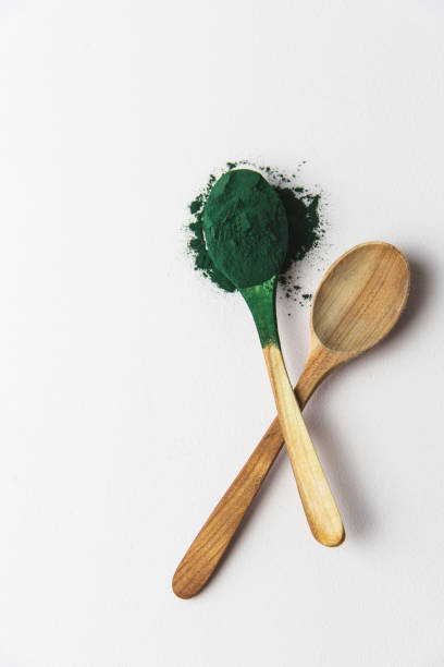 wooden spoons with spirulina powder, superfood on a white background, vertical, full spoon - chlorella spirulina bacterium algae nutritional supplement imagens e fotografias de stock