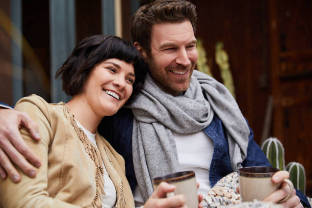 istock Couple drinking coffee on a bench outside their home on a cool morning 1210799302