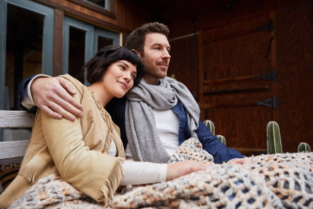 istock Loving couple wrapped in a blanket while sitting outside their home 1210799567