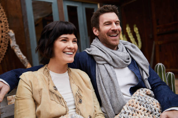 istock Laughing young couple sitting outside wrapped in a blanket 1210800515